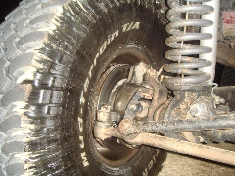 1992 Ford Bronco - A close-up view of the front suspension and a large, muddy off-road tire on a 1992 Ford Bronco. The tire has white lettering that reads "BF…
