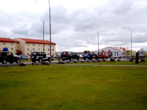 1996 Ford Bronco - A procession of vehicles, including SUVs and ambulances, is parked in a lot under a cloudy sky.