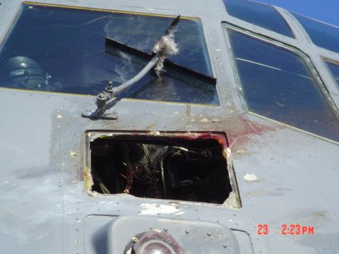 1978 Ford Bronco - Close-up view of the damaged cockpit of a gray aircraft, showing a large hole in the fuselage and shattered windows. Red liquid is splatter…
