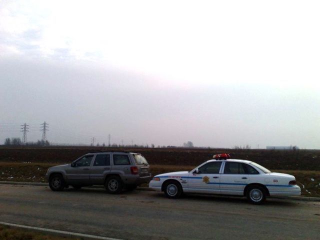 Photo of a silver Jeep Grand Cherokee stopped behind a Crown Victoria police car on a highway