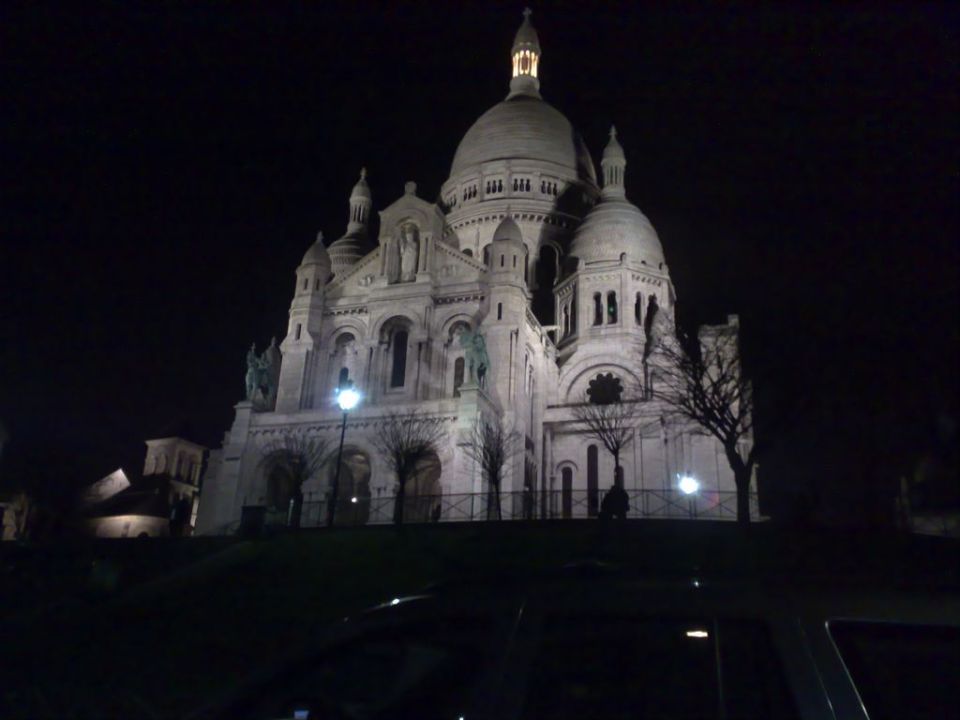 Night photo of the floodlit Sacre-Coeur basilica on a hill