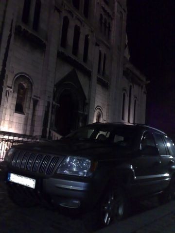 1991 Ford LTD Crown Victoria - Nighttime photograph of a Jeep beside a lit church, not a technical document.