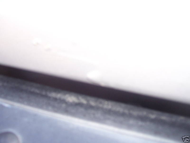 Close-up of a white vehicle panel edge with a worn rubber seal.