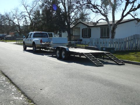 1991 Ford Bronco - A white Ford F-250 Super Duty pickup truck tows a flatbed trailer with ramps down a paved road. The truck is a crew cab with a tan lower bo…