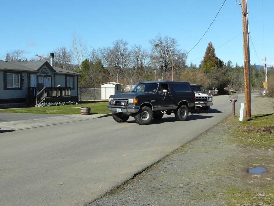 Black Ford Bronco with off-road tires parked on a road.