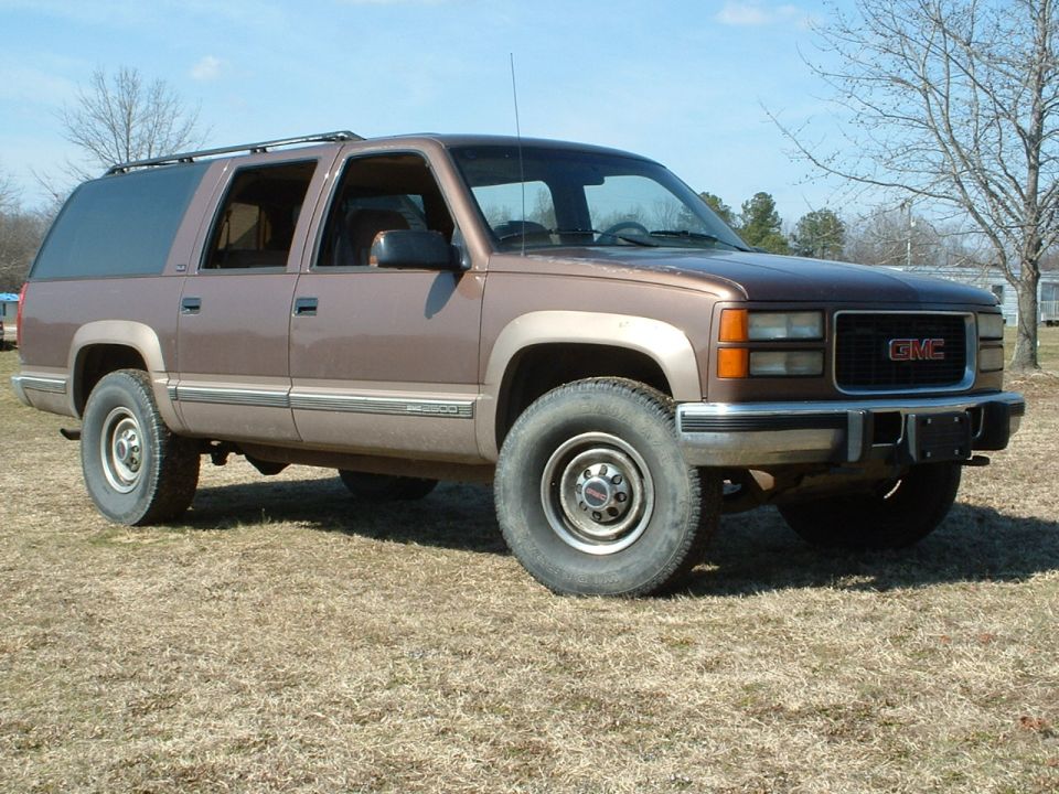 Two-tone brown GMC Suburban K2500 4x4, front 3/4 passenger side on winter grass