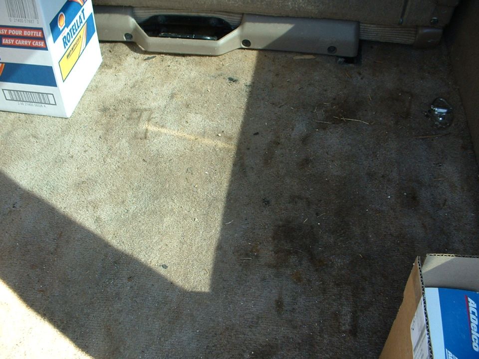 Dirty tan cargo carpet in SUV with Shell Rotella oil case and AC Delco box
