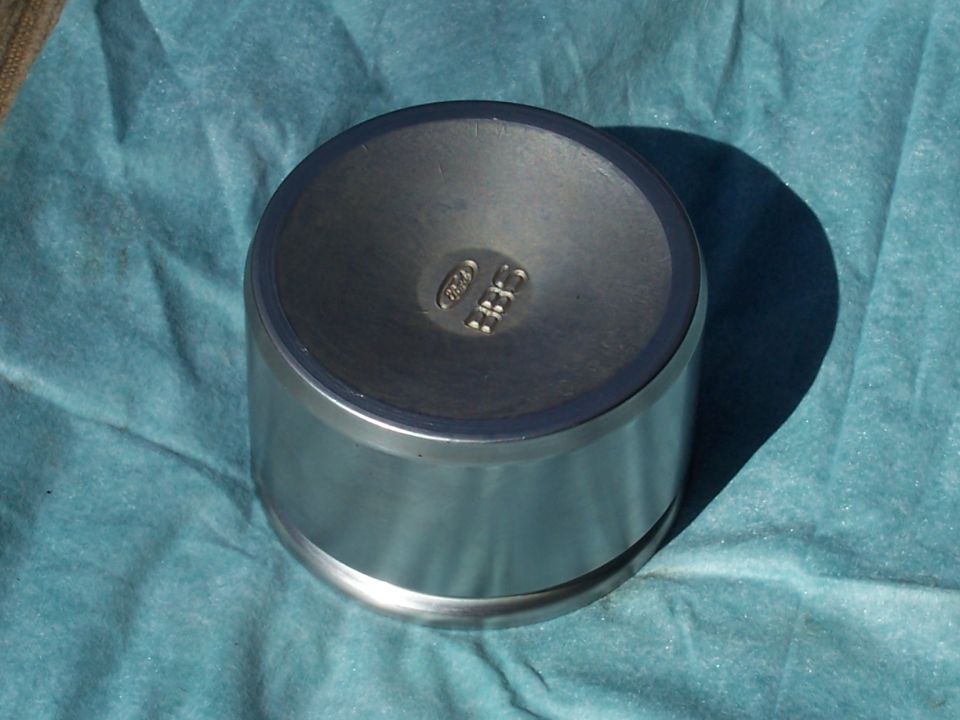 Silver metal cap with Ford logo on blue cloth