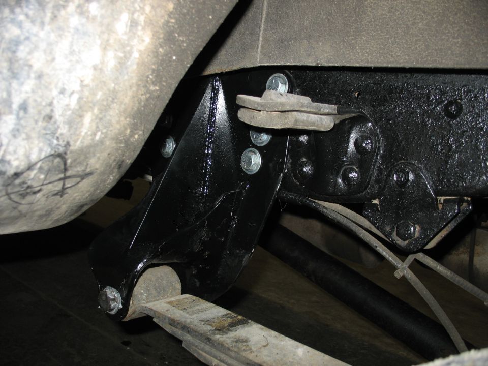 Underside view of vehicle suspension bracket and leaf spring.