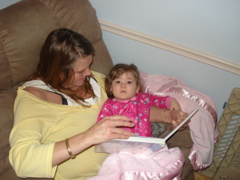 2000 Ford Crown Victoria - A woman is sitting in a chair reading a book to a young child.