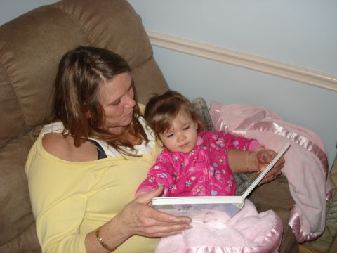 2000 Ford Crown Victoria - A woman and a young child are sitting on a couch and reading a book together. The child is wearing a pink jacket with flowers and hearts on…