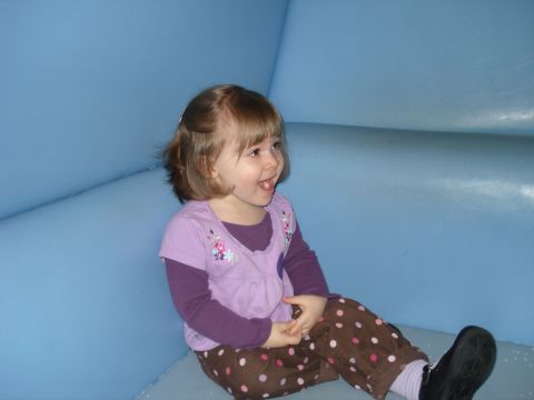 2000 Ford Crown Victoria - A young girl with brown hair is sitting and laughing in front of a blue background. She is wearing a purple shirt with a floral design and…