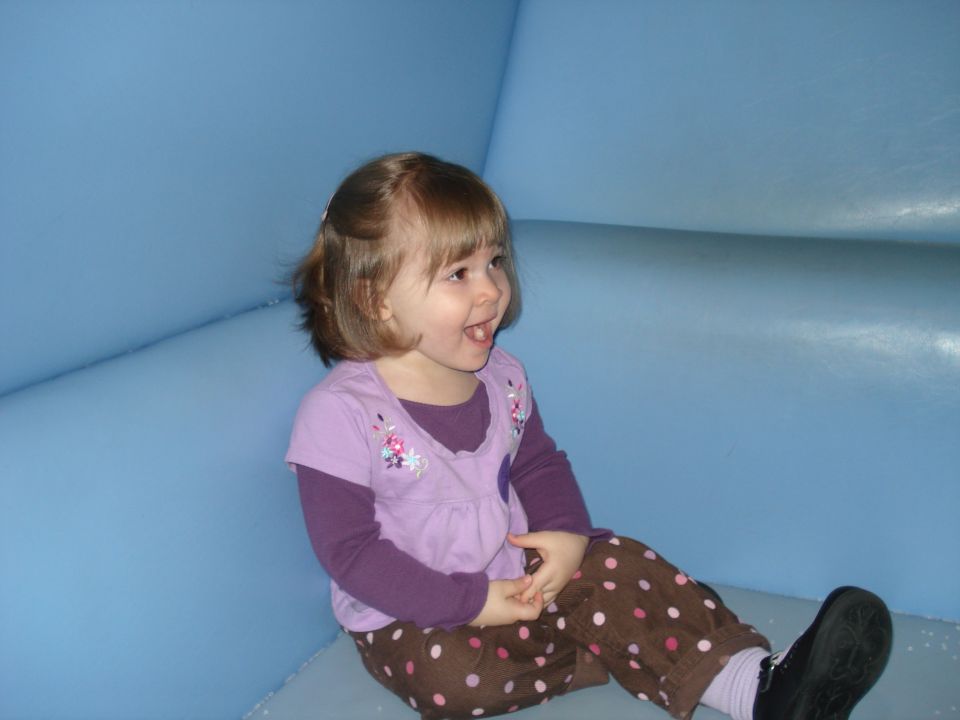 Young girl laughing, wearing purple shirt and polka dot pants