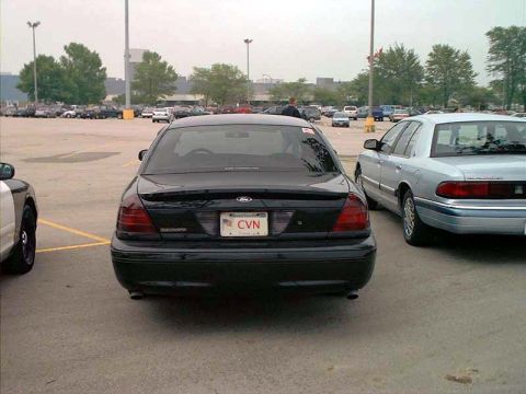 2000 Ford Crown Victoria - A black 2000 Ford Crown Victoria is parked in a lot, showing its rear end and a CVN license plate.
