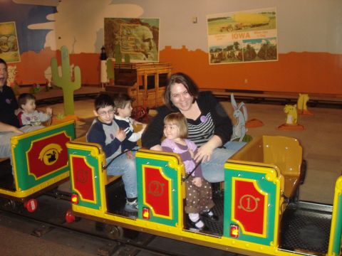 2000 Ford Crown Victoria - A group of people, including adults and children, are riding on a colorful amusement park train ride.
