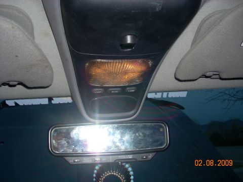 2004 Ford Ranger - The interior of a vehicle shows the overhead console with a reading light and buttons, a rearview mirror, and part of the dashboard. A date…