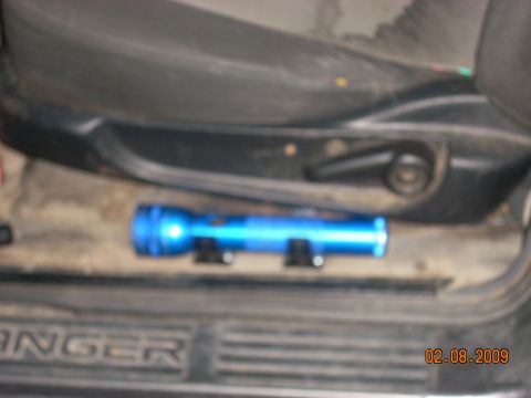 2004 Ford Ranger - A blue flashlight is mounted on the floor of a vehicle, below the driver's seat. The vehicle appears to be a pickup truck, with the word "R…