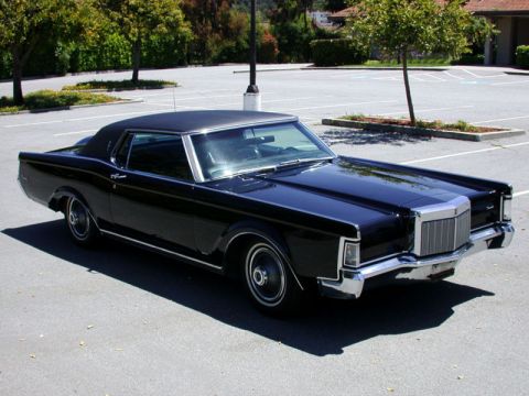 1988 Mercury Grand Marquis - A black, two-door Lincoln Continental Mark V is parked in an outdoor asphalt lot. The car is viewed from a 3/4 front angle, showcasing its…