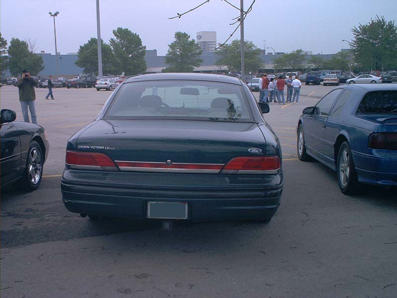 Dark green Ford Crown Victoria parked in a lot. Another blue car is to its right