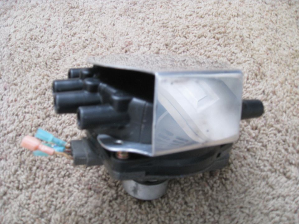 Black distributor cap with silver shield and wire connectors on carpet