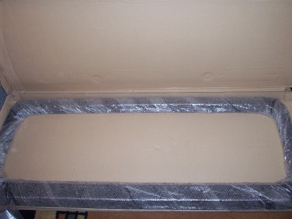 Black automotive part wrapped in bubble wrap inside a cardboard box