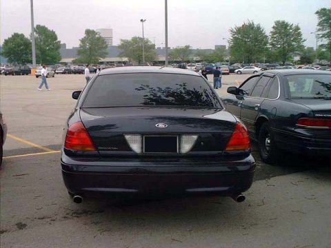 2000 Ford Crown Victoria - A black Ford Crown Victoria is parked in a lot, with another similar vehicle to its right.