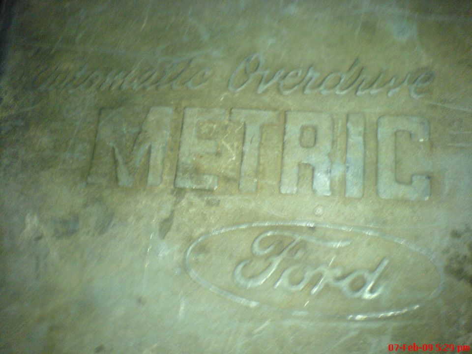 Cast metal part embossed with Ford logo and METRIC Overdrive lettering