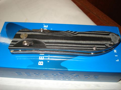 2000 Ford Crown Victoria - A folding knife with a black and gray striped handle rests on top of a blue box with "BENCHMADE LIMITED" printed on it.