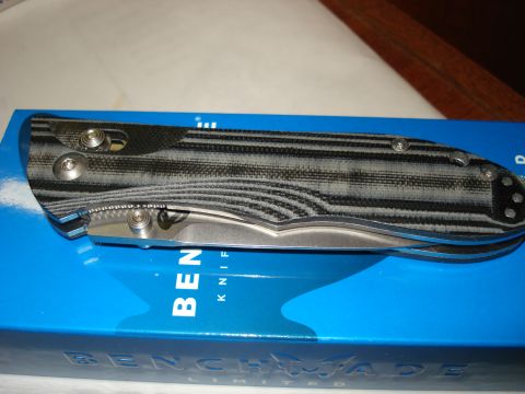 2000 Ford Crown Victoria - A close-up shot of a folding knife with a gray and black striped handle resting on a blue box with "BENCHMADE KNIFE" printed on it.