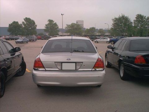 2000 Ford Crown Victoria - A silver 2000 Ford Crown Victoria is parked between two other vehicles in an outdoor lot.
