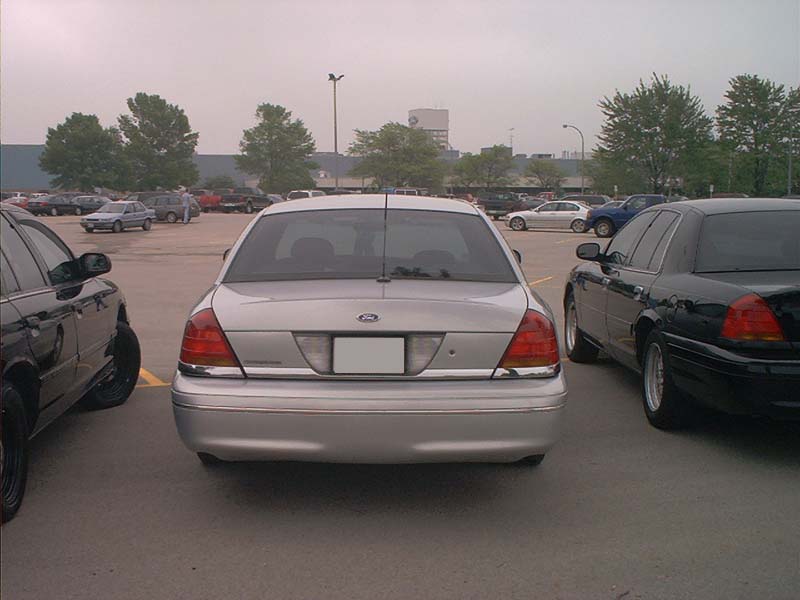Silver 2000 Ford Crown Victoria parked in a lot, rear view. Chrome trim on bumper and trunk