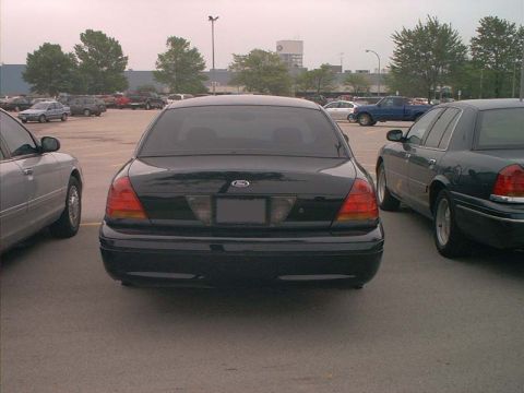 2000 Ford Crown Victoria - The rear of a black 2000 Ford Crown Victoria is visible in a parking lot, with other vehicles nearby.