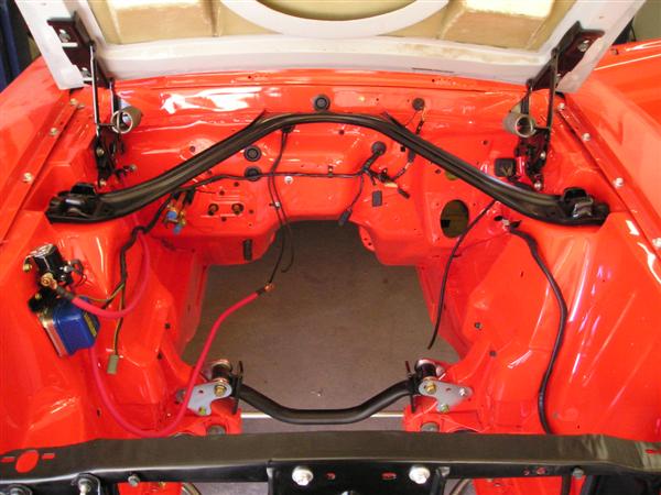 Orange engine bay with black sway bar, wiring, and components