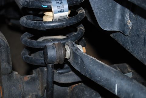 2008 Jeep Wrangler - A close-up view of the rear suspension of a 2008 Jeep Wrangler, showing the coil spring and sway bar end link with a bolt and nut connectio…