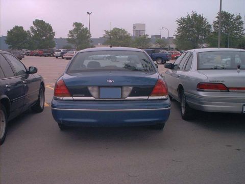 2000 Ford Crown Victoria - Two Ford Crown Victorias are parked side-by-side in a parking lot.