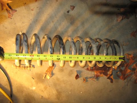 1978 Ford Bronco - Photo of a coil spring measured with a tape measure on the ground, not a technical document.