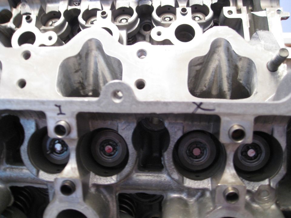 Engine cylinder head showing intake ports and valve openings. "1" marker visible.
