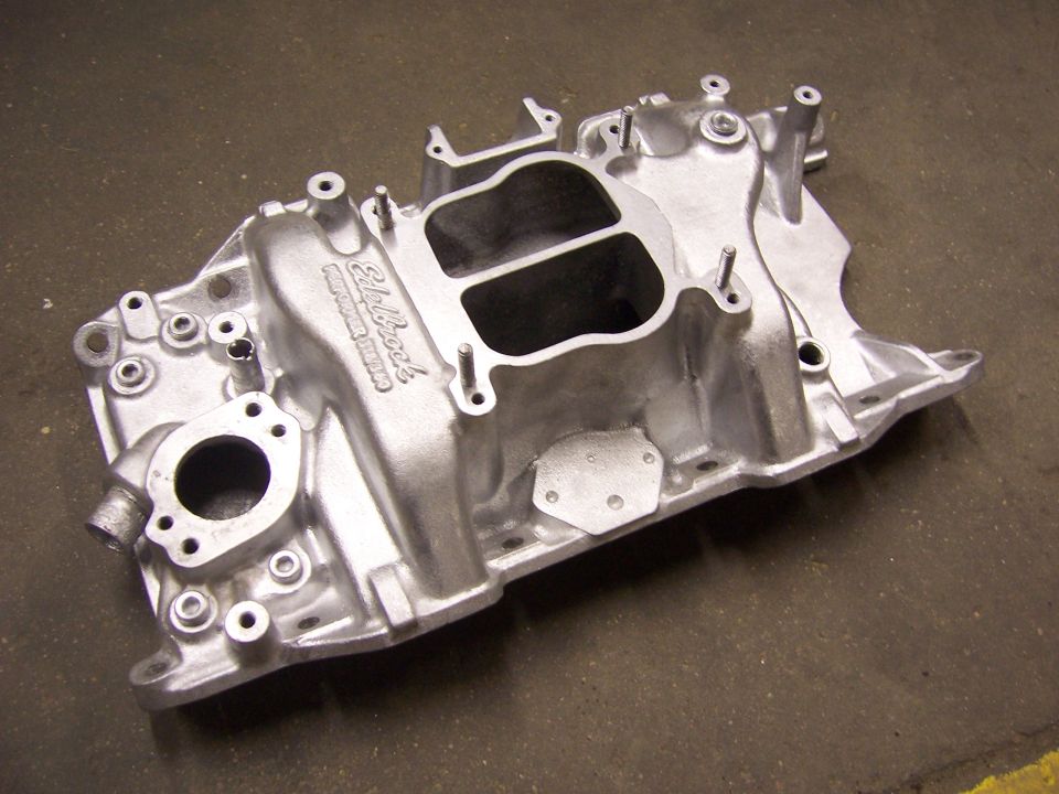 Bare aluminum Edelbrock Performer intake manifold on a concrete shop floor