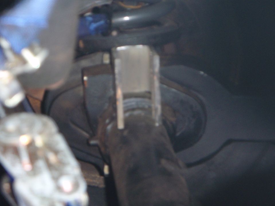 Close-up of a custom metal bracket welded onto a dark cylindrical vehicle part.