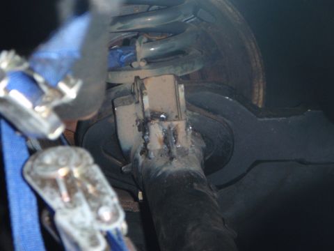 1996 Ford Bronco - Close-up view of a welded metal bracket attached to a vehicle's suspension system, with a blue strap and clamp visible.