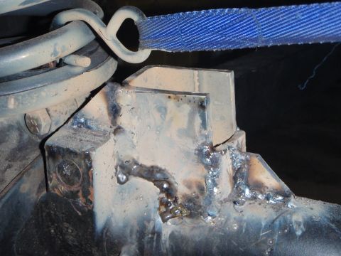 1996 Ford Bronco - A close-up view shows a heavily modified suspension component, likely part of a vehicle's axle or frame, with visible welds and a blue stra…