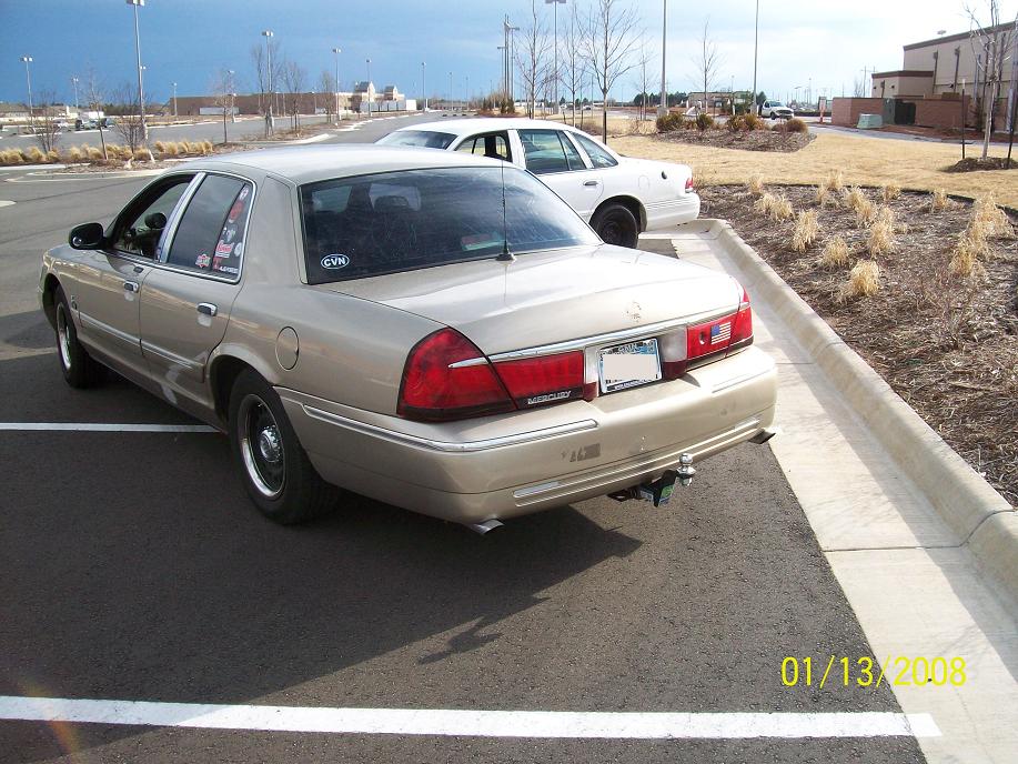 Rear three-quarter photo of a tan Mercury Grand Marquis parked in a lot