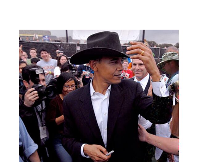 Man in dark suit and black cowboy hat walking through an outdoor crowd of photographers