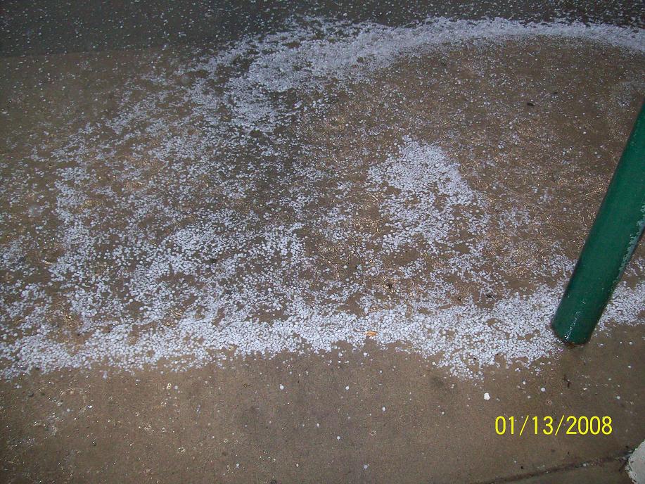 Spilled white granular material scattered on a concrete floor near a green post