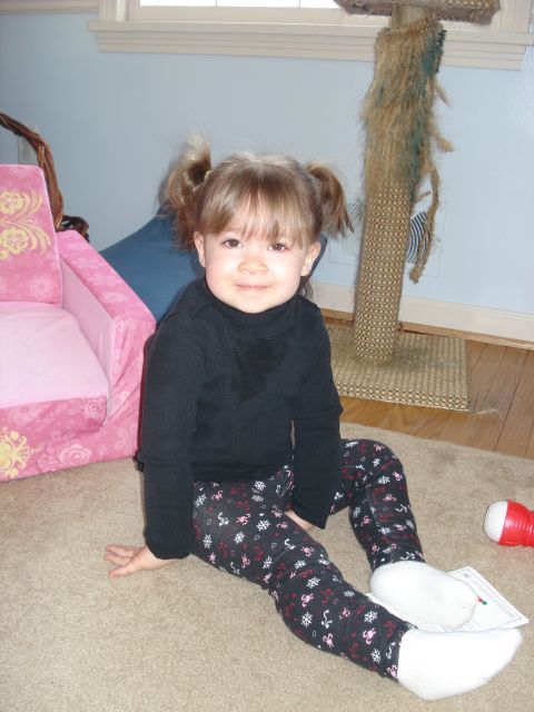 2000 Ford Crown Victoria - A young girl with pigtails sits on a carpeted floor wearing a black turtleneck and patterned leggings. She is next to a pink child's chair…