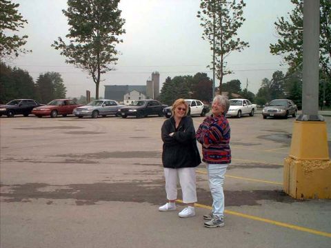 2000 Ford Crown Victoria - A group of cars are parked in a lot, with two women standing in the foreground.