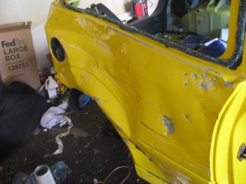 2003 Ford Focus - A severely damaged yellow car panel shows extensive rust and dents, with a FedEx box in the background.