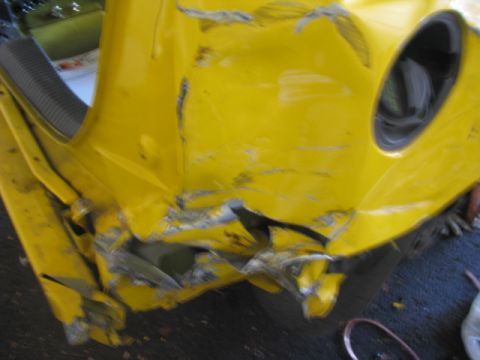 2003 Ford Focus - This severely damaged yellow car part shows extensive damage to the fender and bumper area.