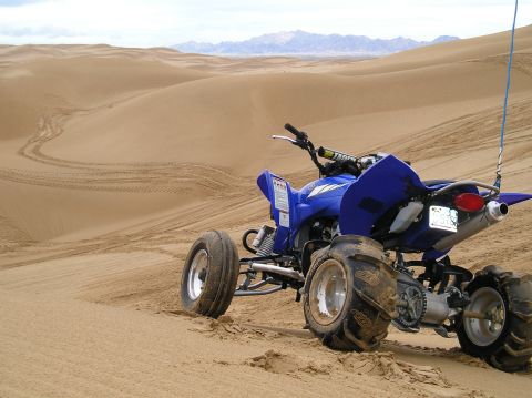 1986 Toyota Hilux - ATV parked on a sand dune, with tire tracks visible in the sand.