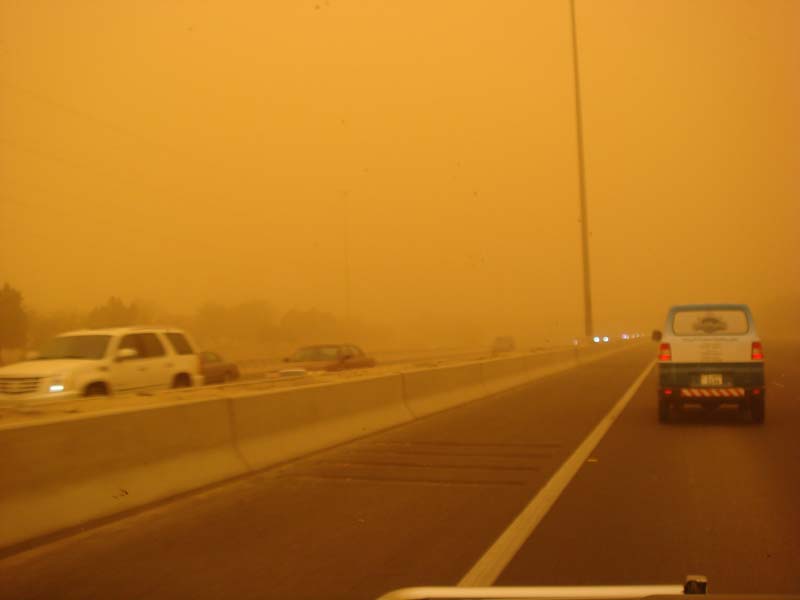 Cars driving on a highway in a sandstorm, visibility is very low